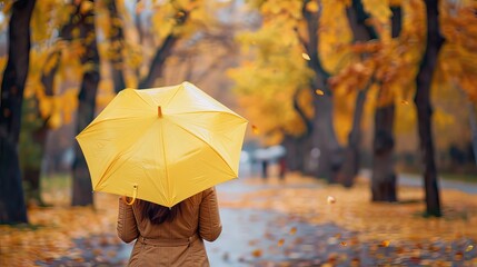 Obraz premium Woman Walking Through Autumnal Park with Yellow Umbrella