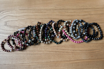 Lots of handmade natural stone bracelets on a wooden table. Close-up. Variety of stones. High...