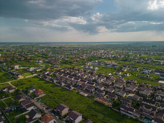 Suburban settlements on the plain. A village seen from above from the drone. Houses gathered on the vast plain cultivated by farmers with various cereals in the spring season
