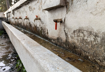 Unhygienic Water taps in a public school of Uttar Pradesh, India. The row of old faucet for water...