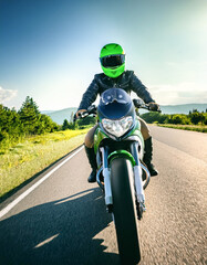 man riding green motorcycle on summer road