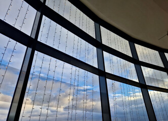 garland, curtain, snowdrifts of light LED chains hanging in front of the glass facade of building. wind blows and you ripple. lots of hanging lights in stripes. view from below. design implementation