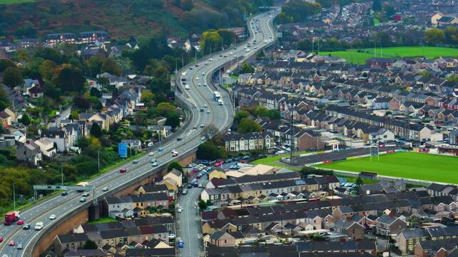 Traffic Moving Steadily Along M4 Motorway Through Port Talbot with Rows of Typical Welsh Suburban Houses and City Streets 4K