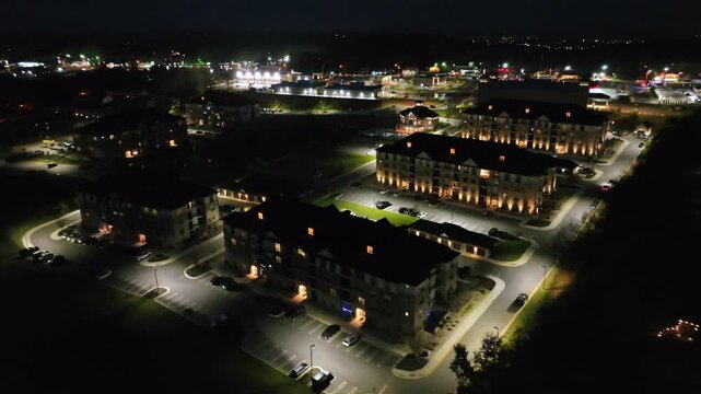 Lighting apartment houses in suburb of american town at night. Aerial top down shot. Parking cars in new developed upscale housing area. Cityscape with highway in background. Timberlake, Virginia,USA
