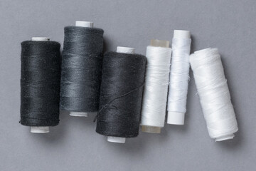Black grey gray thread spools with needle background with copy space for text close-up flat lay top view
