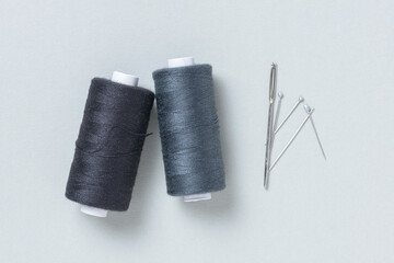 Black grey gray thread spools with needles background with copy space for text close-up flat lay...