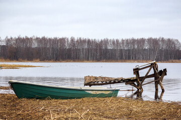 Damaged green fisherman's boat in reeds on the background of the river