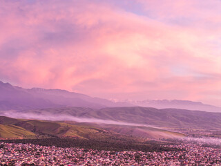 Naklejka premium Drone view of the village and mountains at sunset. Beautiful clouds on the sky. Evening cityscape.