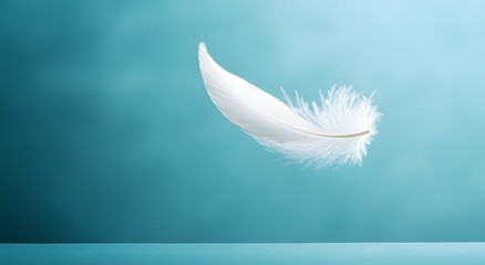 Obraz premium A single floating white feather floats in the air against a light blue background, highlighting the softness of the feather. Representing a feeling of calm and tranquility. It looks very beautiful.