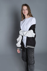 A young girl looks over her shoulder with a gentle expression, her jacket loosely draped around...