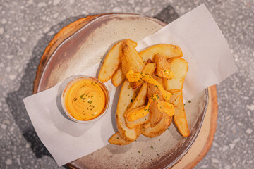 Top view, Deep-fried potato wedges with dipping cheese and tartar sauce on a round plate