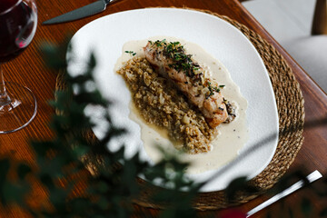 checken roll with mushroom white creamy sauce served on wooden table with red wine in restaurant top view