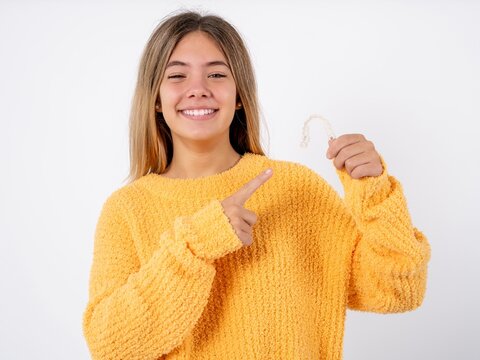 MODEL holding an invisible aligner and pointing at it. Dental healthcare and confidence concept.