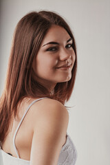 Naklejka premium Young woman with long brown hair looking over shoulder and smili