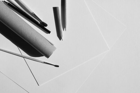 Design Studio Flatlay. Sheets of Paper, Graphite Pencils, Painting Brushes, Kraft Paper Roll Arranged on Desk. Designer Sketching Mockup.	