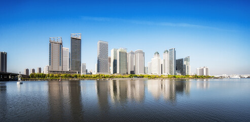 Obraz premium Serene Waterfront Cityscape Under Clear Blue Sky