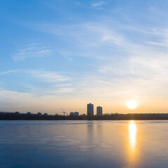 Fototapeta premium winter frozen river covered by snow with forest on coast at the sunset