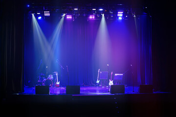 Dark background of the stage with musical instruments illuminated by a blue spotlight.