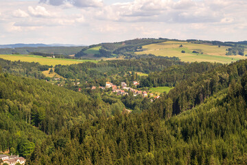 Obraz premium Picturesque countryside view with a small village nestled in a green valley, surrounded by hills