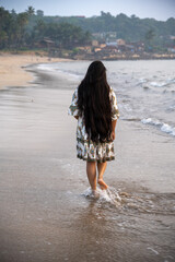 back view of curvy lady walking along the white sand beach with dreamy vibes