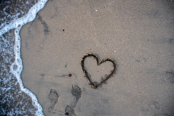 A heart is drawn on the sand on the beach at sunset. Romantic sunset on the beach. Heart shape. Heart symbol. Love.