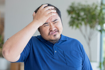 Serious Asian middle aged man with negative facial expression, upset unhappy mid age old real man with failed mood, slapping his head with upset emotion, Frustration and disappointment
