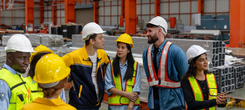 A male foreman gives instruction and job description for the day to his mechanical engineer team next to the iron steel machine. Cooperation among factory workers. Safety brief before the day starts