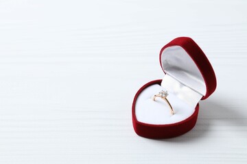 Beautiful shiny gold engagement ring with large diamond gemstone in a rich red velvet box on white...