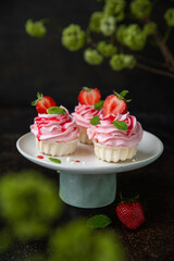 Słodka beza Pavlowa z truskawkami i kremem truskawkowym na ciemnym tle. © Dorota
