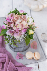 Różowa hortensja w rustykalnym dzbanku na białym, drewnianym tle. © Dorota