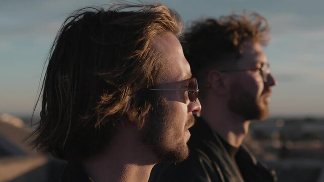 Close up of two men with windswept hair and sunglasses gazing into the horizon, Montpellier, France