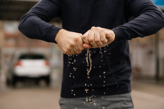 The man is wringing out a microfiber cloth after washing his car, close-up shot.