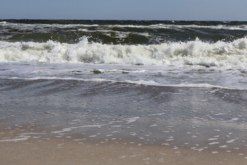 Ocean Waves Crashing on Sandy Beach. A vibrant coastal scene featuring waves rolling onto a sandy shore, with a mix of sea foam and wet reflections, capturing the energy of the ocean.