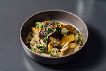 Gourmet dish in focus, featuring grilled meat with garnish in a ceramic bowl. Close-up composition with shallow depth of field