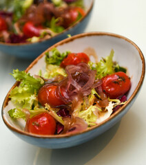 Ensalada con tomates cherry, cebollas y lechuga en un bol azul