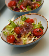 Ensalada con tomates cherry, cebollas y lechuga en un bol azul