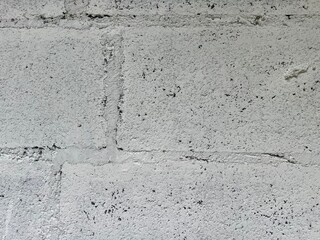 A textured concrete wall with a light gray color, featuring some imperfections and variations in surface finish.