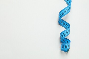 Blue tape measure on a gray background, top view