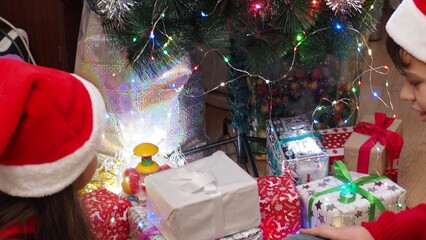 Happy Little Family Exchanging Gifts on Christmas Eve: Brother and Sister Receiving their Gifts. Happy Children Getting New Toys from Mom and Dad, with Family. children enjoy christmas and new year