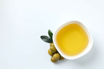 Bowl of fresh olive oil and olives with leaves on white background