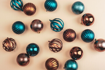Vibrant assortment of teal and copper Christmas baubles on a beige background, emphasizing a modern festive color palette. Top view, flat lay, copy space