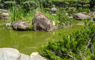 GPond with emerald water and stone banks. Garden of Russian-Japanese friendship with unique Japanese plants and architectural forms. Garden is decorated with sculptures and Japanese-style buildings.