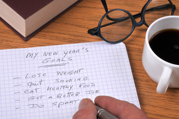 Écrire ses bonnes résolutions en anglais sur un cahier à spirales avec un stylo en gros plan