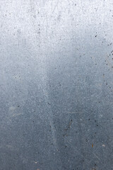 metal wall. It is gray in color with small black dots and spots that may be signs of rust or dirt.