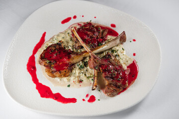 lamb chop stick grilled with red cherry sauce setted with porridge and topped with seasonal herbs, served on white plate and background cloth