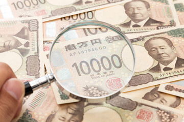たくさんの一万円札と虫眼鏡