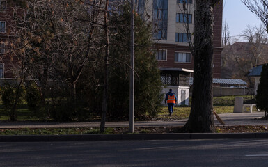 a worker in an orange vest on the autumn street of the city