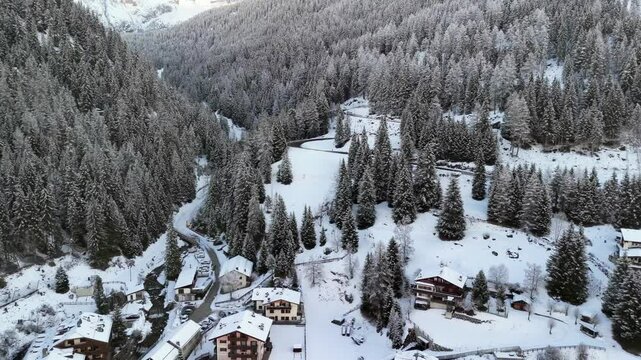 Canazei, Italy: Aerial view of ski resort in snowy Dolomites. Charming town landscape with chalets and hotels surrounded by snow-capped peaks, sunny day, clear blue sky
