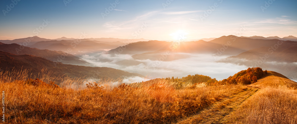 Sticker The bright morning sun shines over the mountains and the valley with fresh fog. Carpathian mountains, Ukraine.