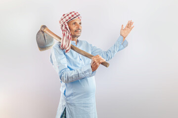 indian senior farmer looking up while holding garden hoe on his shoulder against white background